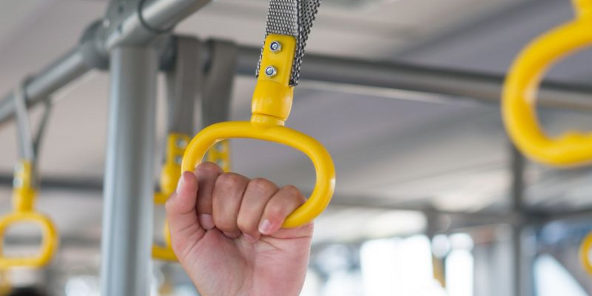 Hand, die sich an einem Haltegriff im Bus festhält