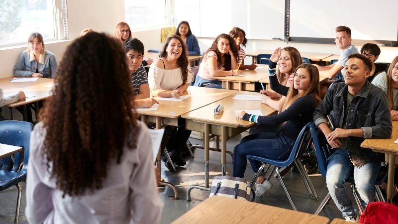 Lehrerin steht vor einer Klasse mit Jugendlichen