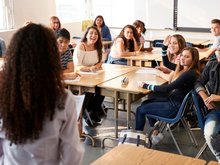 Lehrerin steht vor einer Klasse mit Jugendlichen