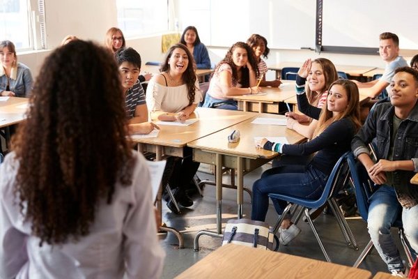 Lehrerin steht vor einer Klasse mit Jugendlichen