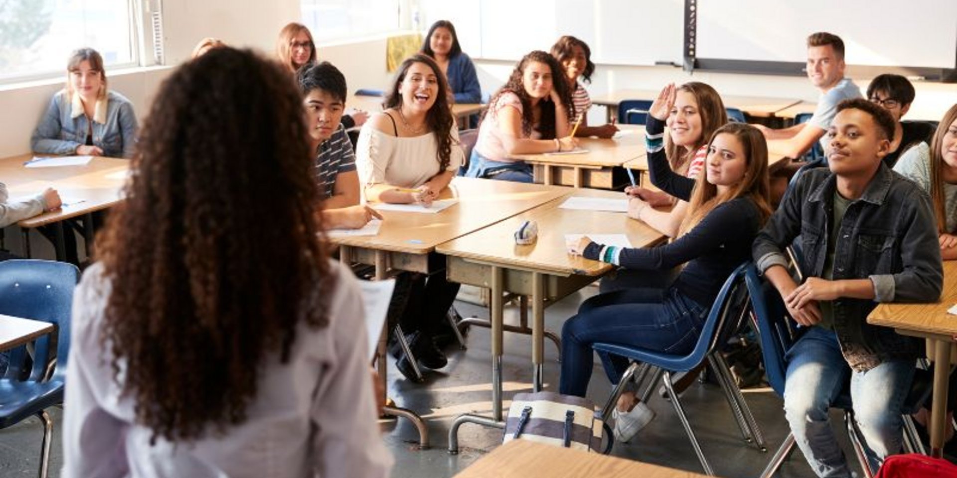 Lehrerin steht vor einer Klasse mit Jugendlichen