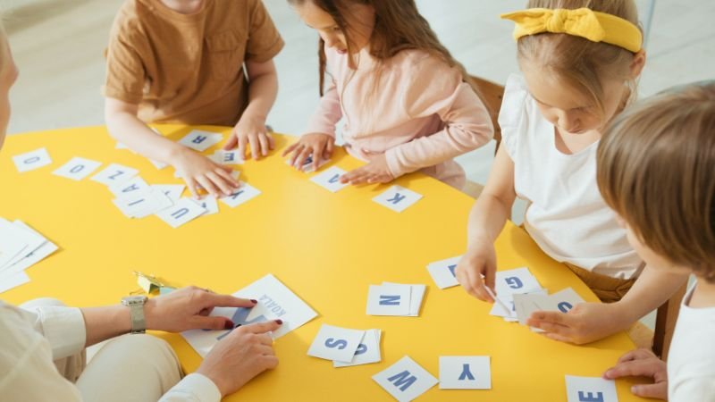 Kinder lernen gemeinsam an einem Tisch Buchstaben