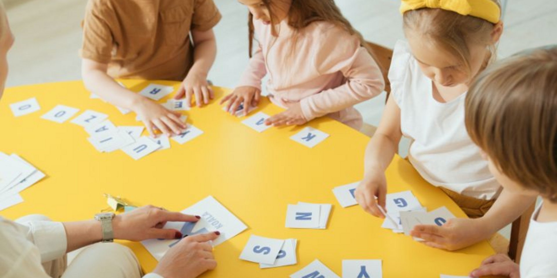 Kinder lernen gemeinsam an einem Tisch Buchstaben