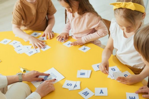 Kinder lernen gemeinsam an einem Tisch Buchstaben