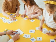 Kinder lernen gemeinsam an einem Tisch Buchstaben